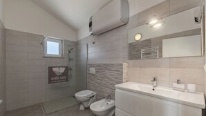A modern bathroom with a toilet, bidet, sink, and a towel rack. - Wabi Sabi Apartment 3 (Krk)