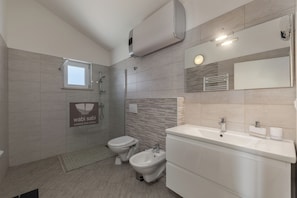 Ein modernes Badezimmer mit Toilette, Bidet, Waschbecken und Handtuchhalter.