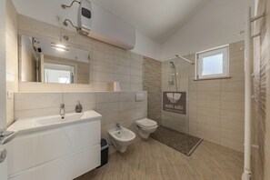 Ein modernes Badezimmer mit Badewanne, Bidet, Toilette und Duschbereich.