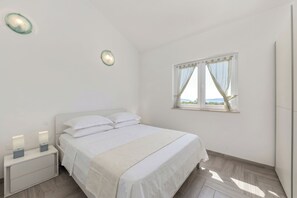 Ein Schlafzimmer mit einem Bett, Nachttischen, einem Fenster und einer Wandleuchte.