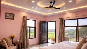 Une chambre à coucher avec un lit, un ventilateur de plafond et de grandes fenêtres avec des rideaux.