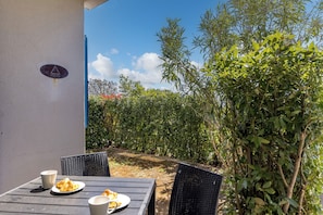 An outdoor table with plates and cups, a chair, and a sign on a wall. - Wabi Sabi Apartment 6 (Krk)