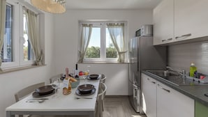 Et moderne køkken med spiseplads, rustfrie stålgrebe og udsigt til grønne områder.