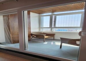 Una habitación con un ventanal grande, techo de madera y dos sillas de mimbre.