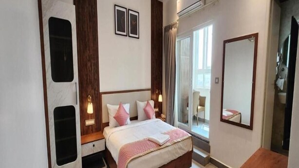 A bedroom with a bed, bedside tables, a mirror, and a window with curtains.