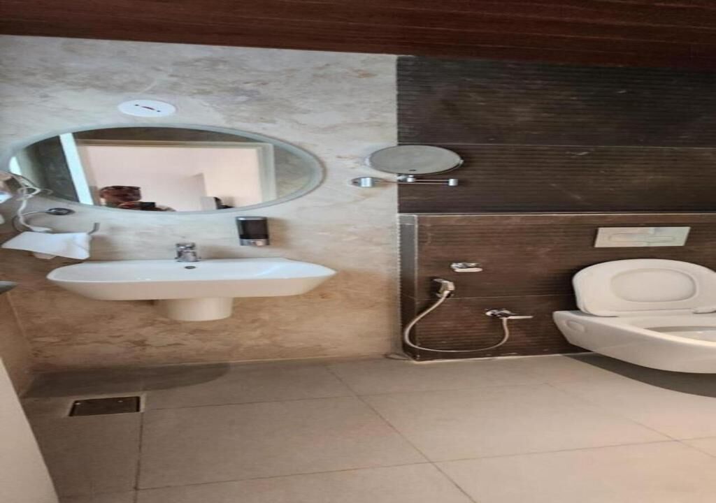 A bathroom with a sink, mirror, toilet, and shower.