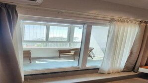 A room with a sliding glass door leading to a balcony with a table and chairs.