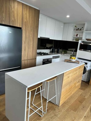Une cuisine moderne dotée d’un îlot central, de meubles en bois et d’un four encastré.