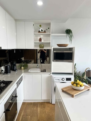 A modern kitchen with white cabinets, a built-in oven, a microwave, and a sink. - Quiet 1 Bedroom 1 Bathroom plus Study Close to Hospitals Free Parking (Heidelberg)