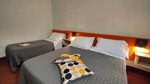 A hotel room with two single beds, a nightstand with a lamp, and a wall-mounted TV. - A comfortable standard triple room just a stone's throw from the center of Volterra (Volterra)