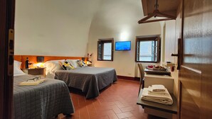 A bedroom with two beds, a TV, a desk with a chair, and a window. - A comfortable standard triple room just a stone's throw from the center of Volterra (Volterra)