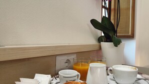 A breakfast tray with croissants, coffee, and orange juice on a table with a vase of purple flowers and a wooden door in the background. - A comfortable standard triple room just a stone's throw from the center of Volterra (Volterra)