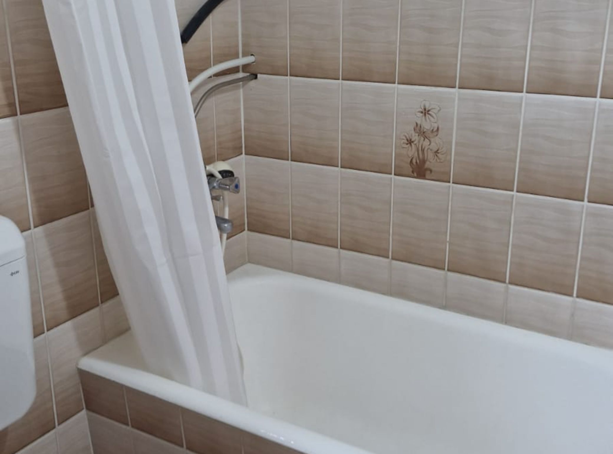 A bathroom with a bathtub, shower curtain, and tiled walls.