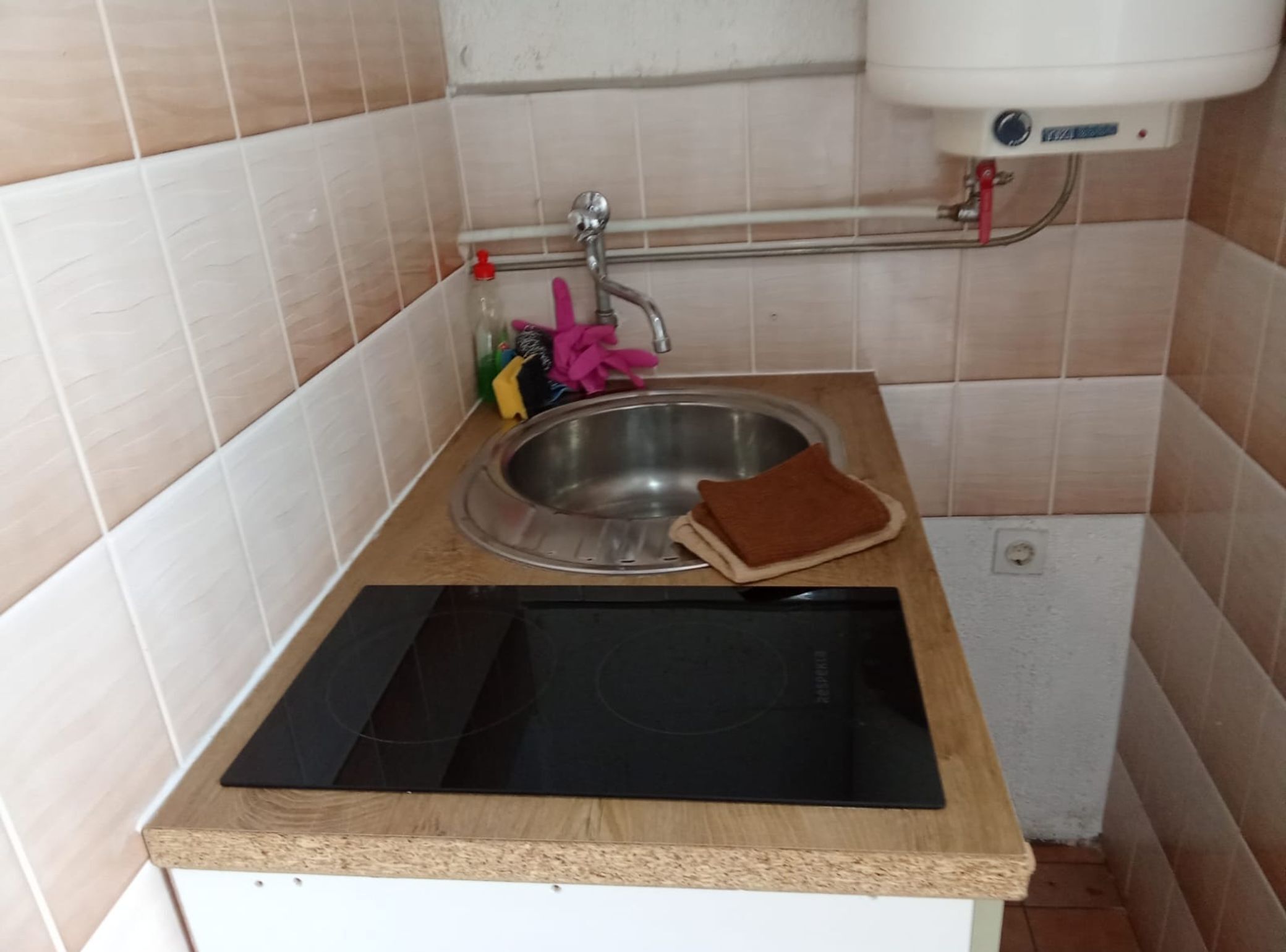 A kitchen with a stainless steel sink, a wooden countertop, and a black induction cooktop.