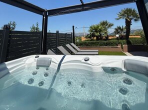 Ein Whirlpool mit freiem Blick auf einen angelegten Garten und Palmen im Hintergrund.