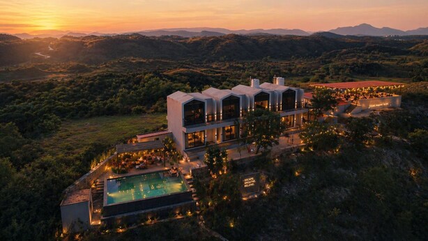 Un hôtel moderne doté d’une piscine, entouré d’une végétation luxuriante et de montagnes.
