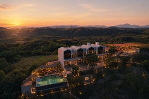 A modern hotel with a pool, surrounded by lush greenery and mountains. - VANVASS - A Forest Resort By Rovers (Nathdwara)