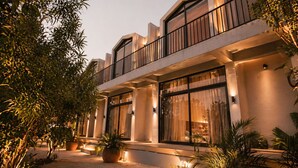 Un hôtel moderne doté d’une cour intérieure, de grandes fenêtres et de plantes en pot.