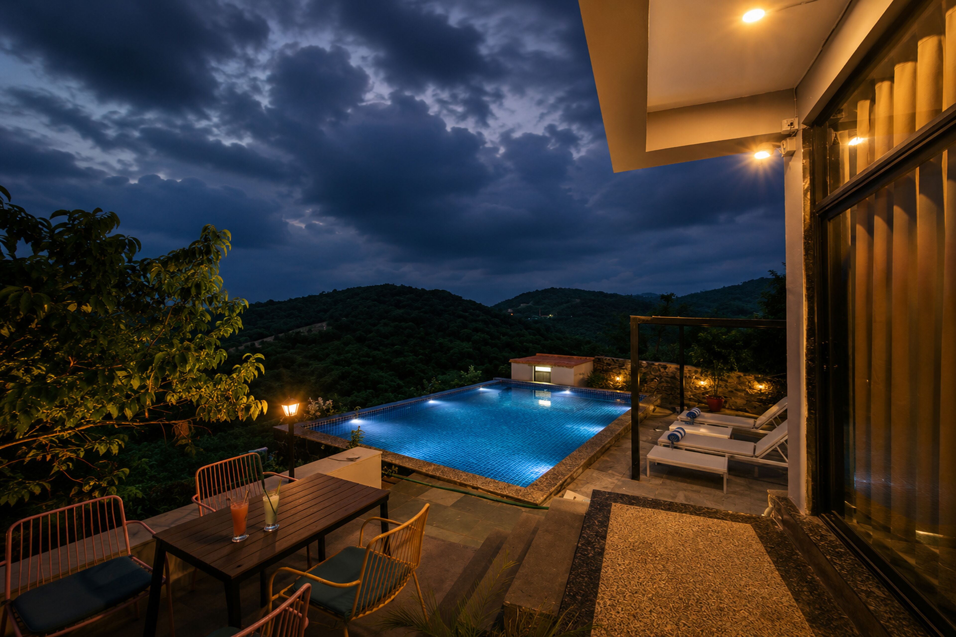 Piscina com vista para as montanhas, área de refeições com cadeiras e área de estar com espreguiçadeiras.