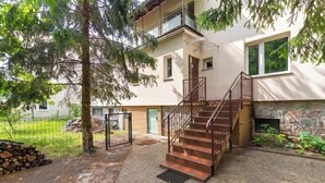 Monikerroksinen rakennus, jossa on portaikko, joka johtaa parvekkeelle, kiviseinä ja pieni puutarha-alue.
