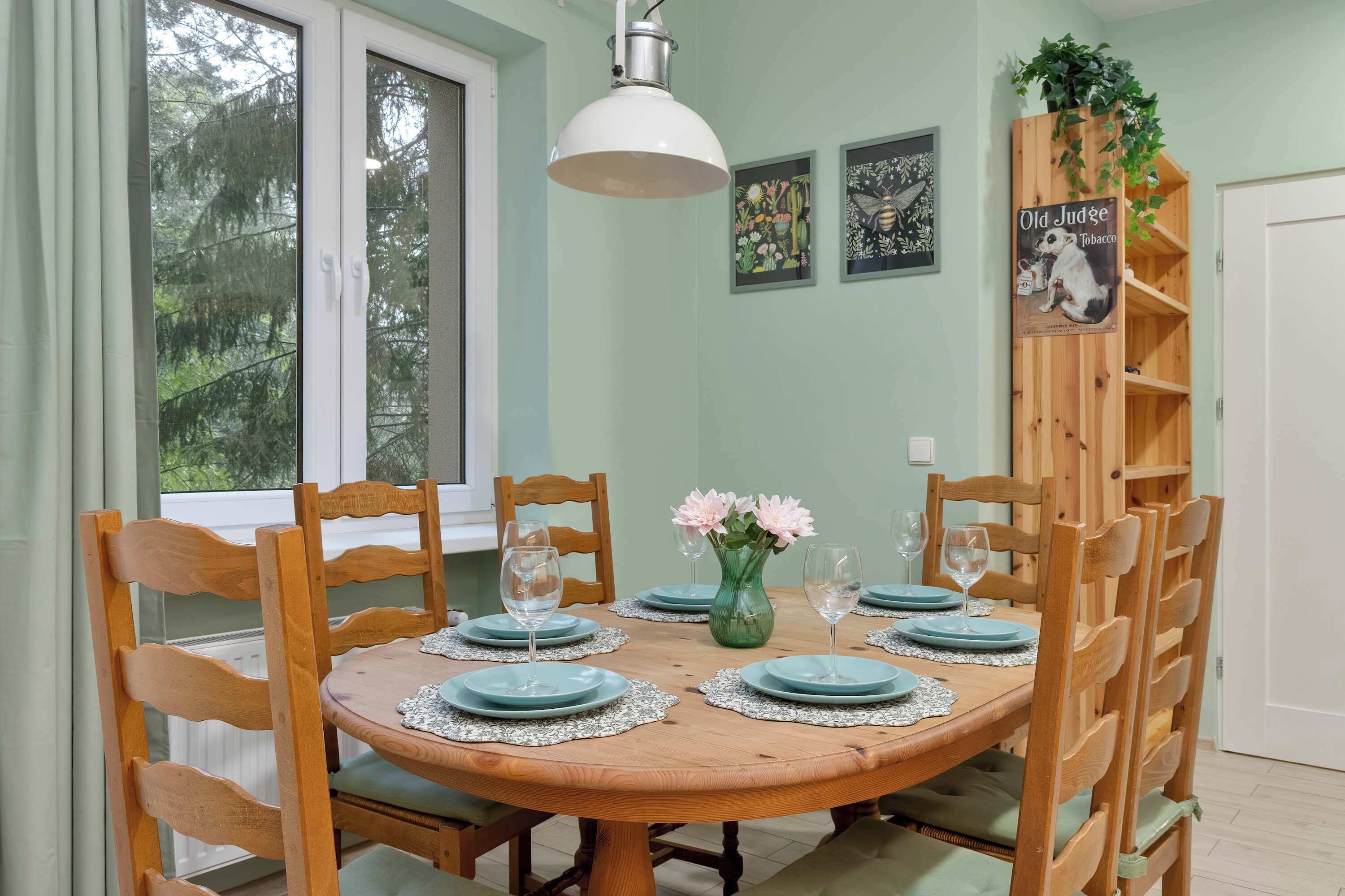 A dining table set with plates, glasses, and a vase of flowers.