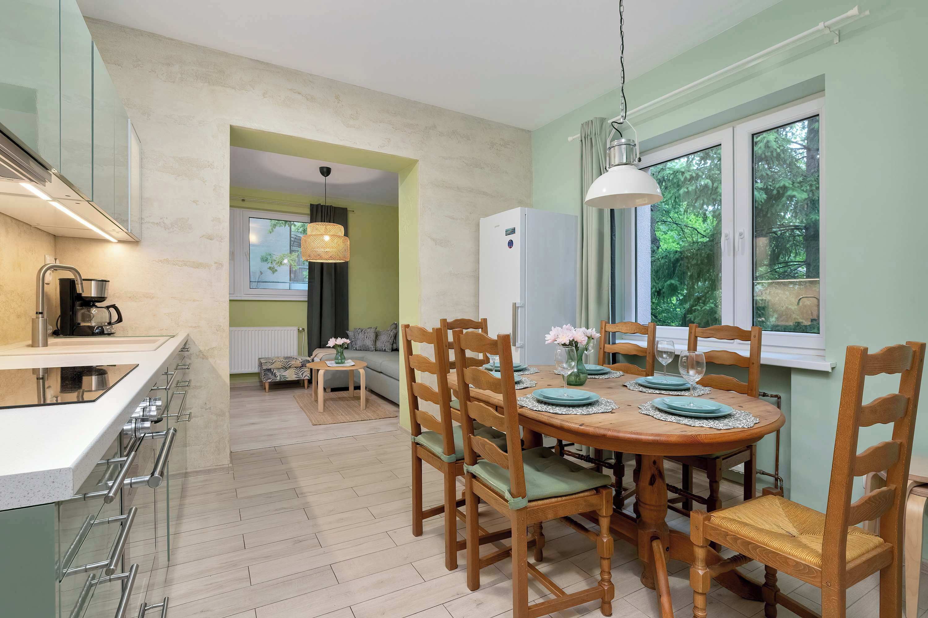 A kitchen with a built-in stove, a dining table with chairs, and a refrigerator.
