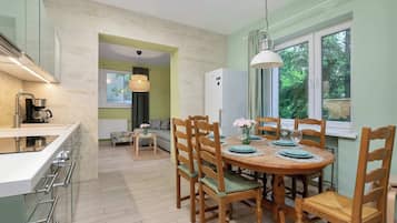A kitchen with a built-in stove, a dining table with chairs, and a refrigerator.