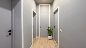 Un pasillo estrecho con paredes grises, suelo de madera y una planta en maceta.