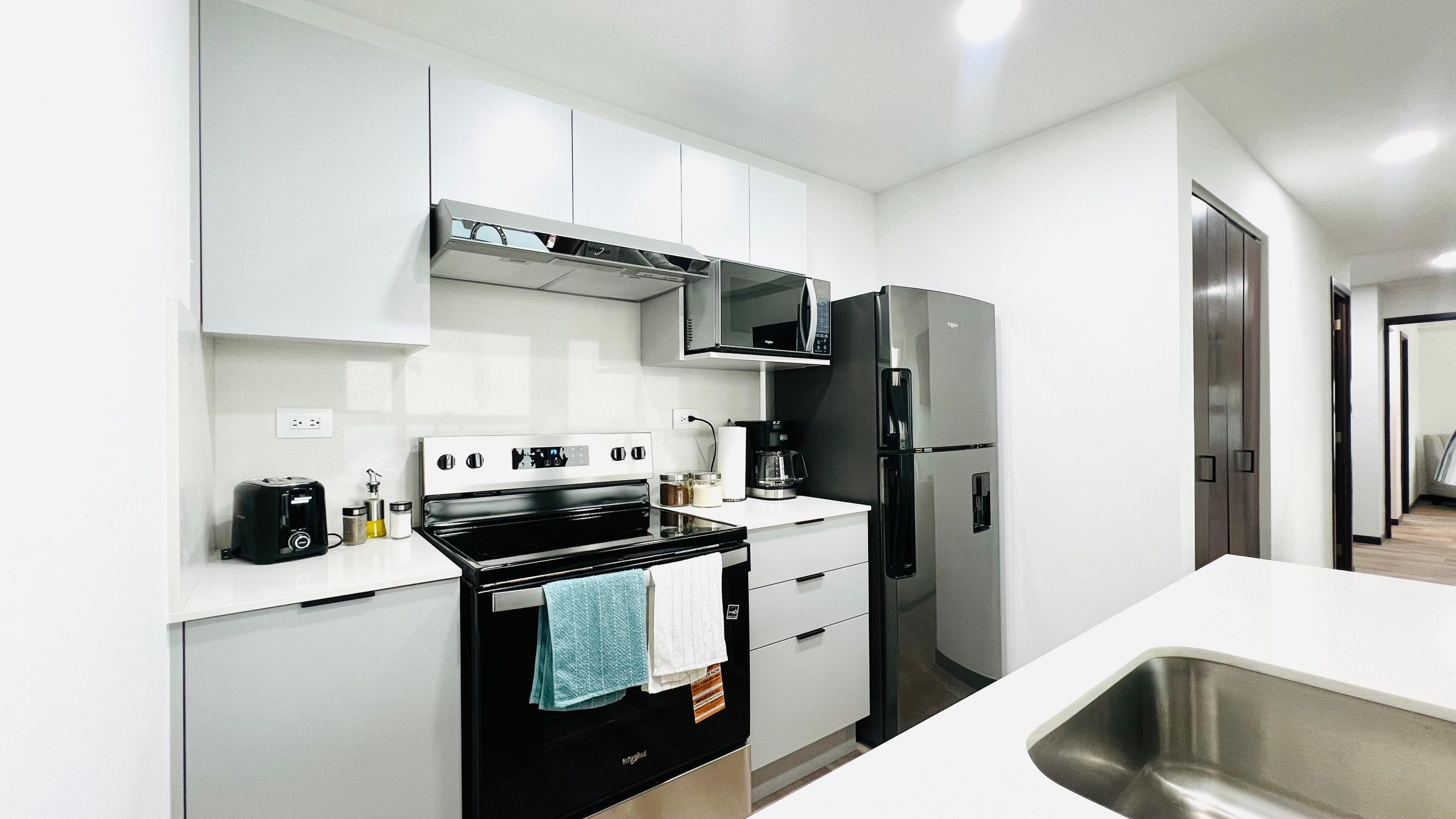 Una cocina moderna con estufa, microondas, refrigerador y pileta.