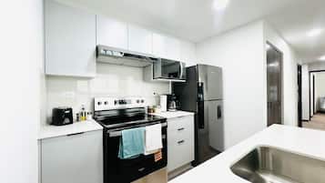 Una cocina moderna con estufa, microondas, refrigerador y pileta.