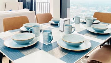 Comedor con mesa dispuesta para cuatro, vista a la ciudad y balcón con puerta.