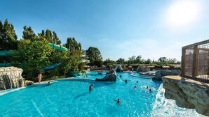 Een zwembad met diverse waterattracties, waaronder watervallen en rotsformaties.