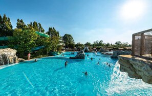 Ein Schwimmbecken mit verschiedenen Wasserelementen, darunter Wasserfälle und Felsformationen.