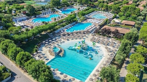 Luchtbeeld van een resort met meerdere zwembaden, ligbedden en een waterpark.
