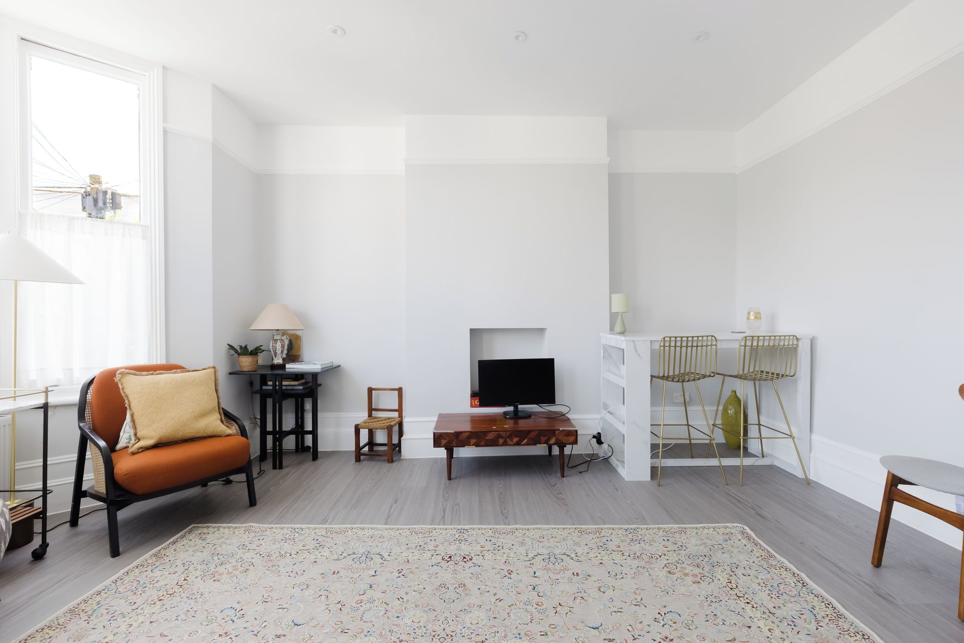 A modern living room with a sofa, a coffee table, a TV, and a dining area with chairs.