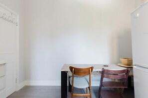 A dining area with a table and two chairs, a white door, and a white wall. - Sunny 3BDR Family Home in Clapham (Greater London)