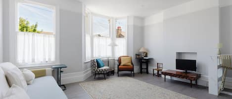 Un salón amplio con un sofá, un sillón y un televisor.
