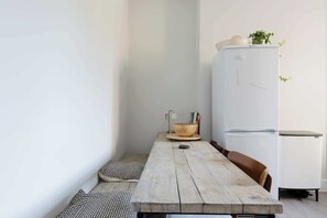 A compact kitchen with a wooden table, a white refrigerator, and a potted plant. - Sunny 3BDR Family Home in Clapham (Greater London)