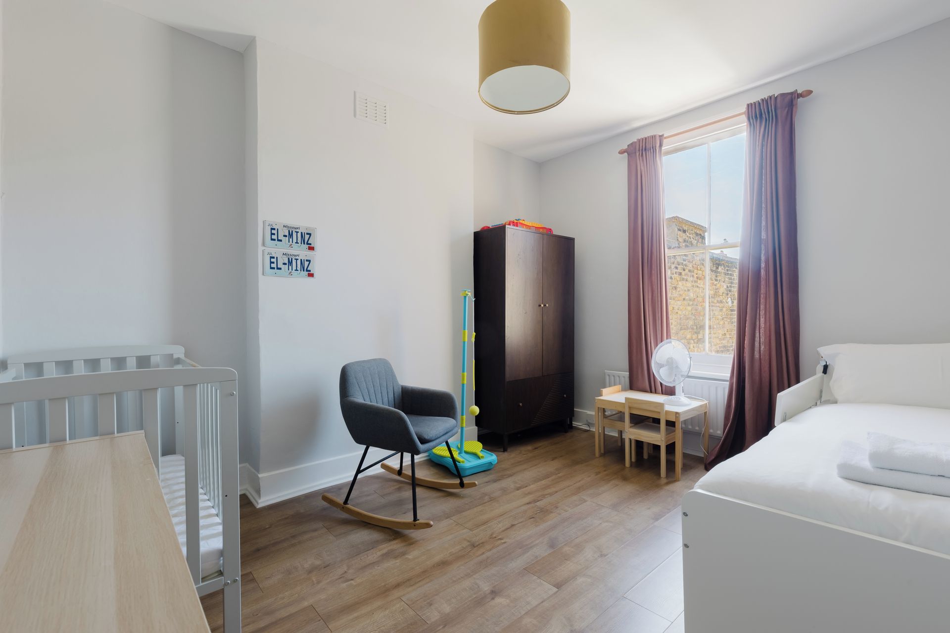 Een kamer met een ledikant, schommelstoel, kledingkast en een bed.