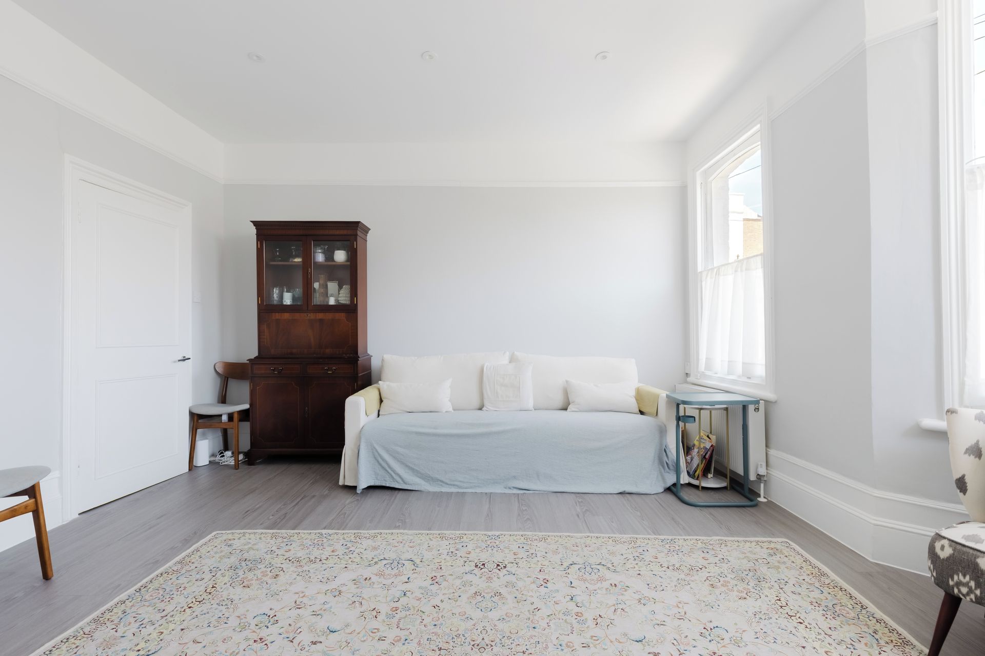 A bedroom with a bed, a wooden cabinet, a window, and a patterned rug.