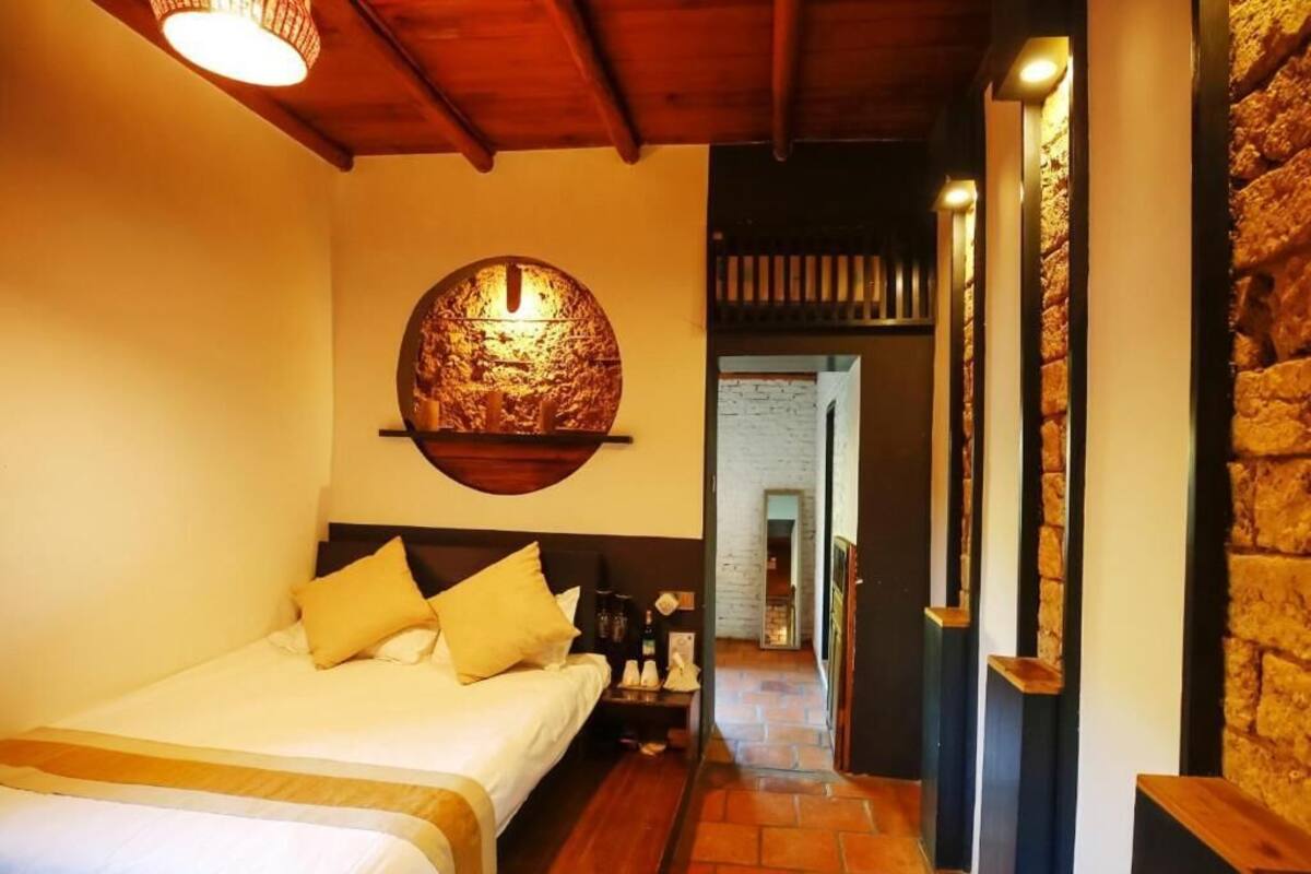 Ein Hotelzimmer mit einem Bett, einer runden Wanddekoration, Holzboden und einer Steinwand.