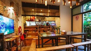 Un café acogedor con mobiliario de madera, un televisor y una pared de ladrillo.