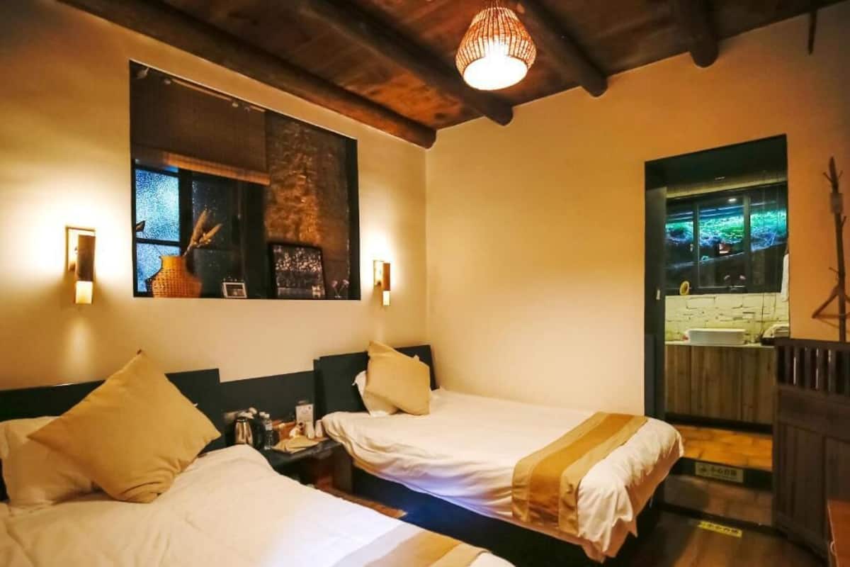 Ein Hotelzimmer mit zwei Betten, Holzboden, einem Wand-Fernseher und einem Fenster mit Blick.