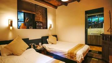 A hotel room with two beds, a wooden ceiling, a wall-mounted TV, and a window with a view.