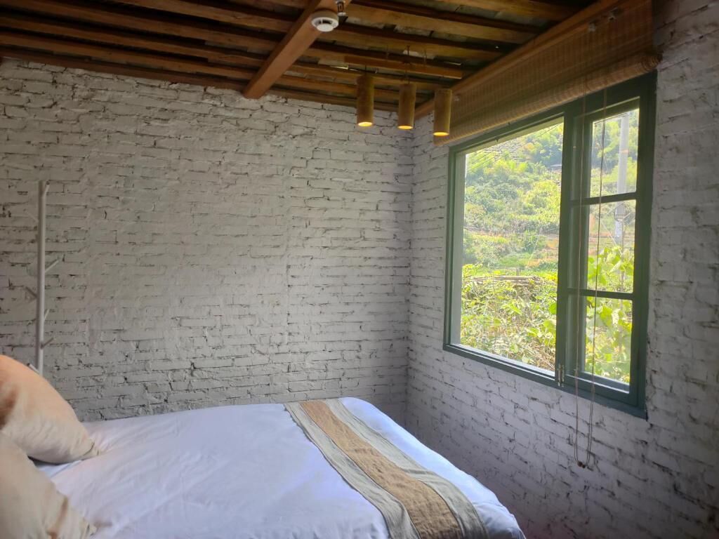Una habitación con una cama, un ventanal con vistas a la vegetación y un techo de madera.
