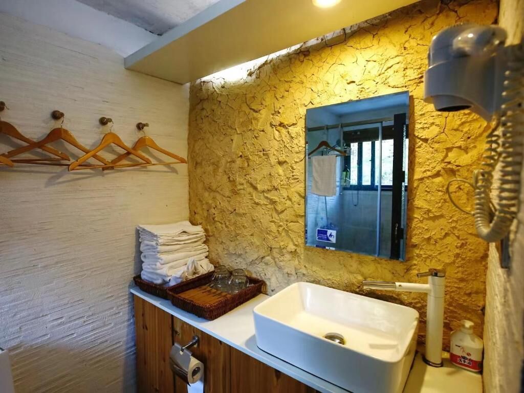 A bathroom with a white sink, a mirror, a towel rack, and a hairdryer.