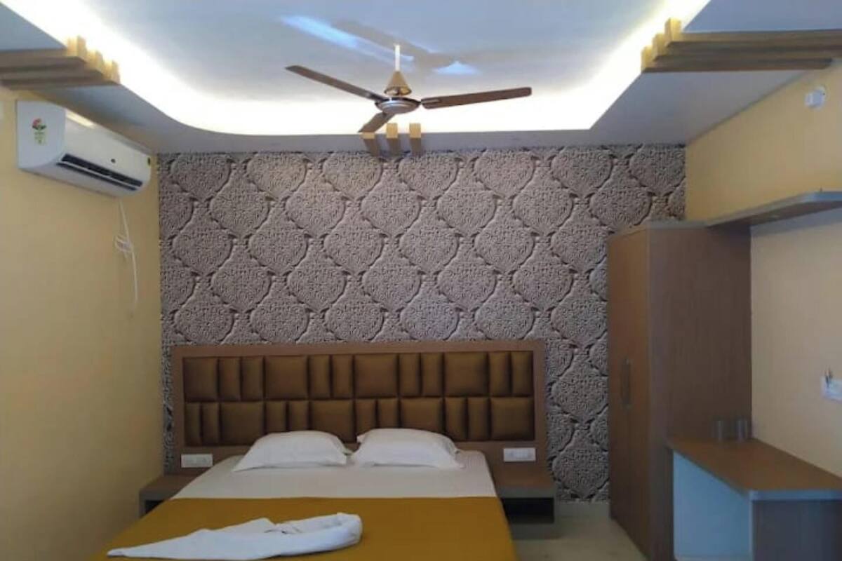 A bedroom with a bed, a ceiling fan, a patterned wall, and a wardrobe.