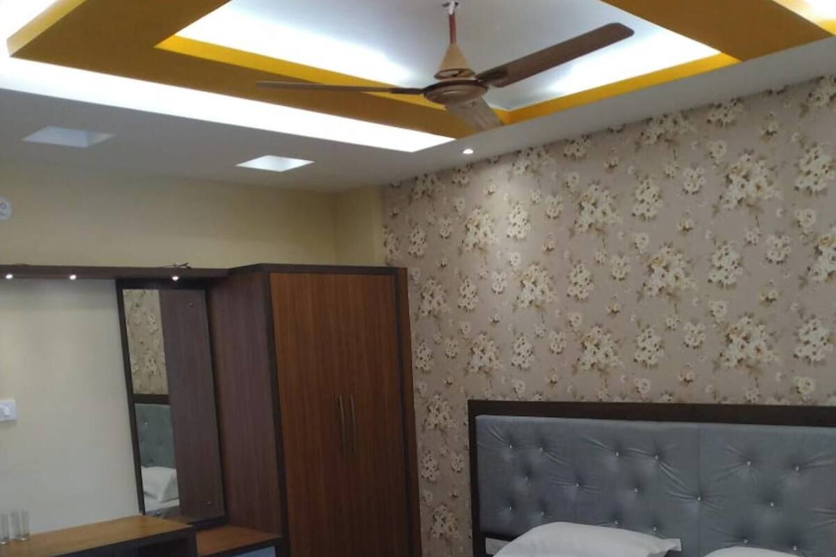 A bedroom with a bed, a wardrobe, a desk, and a ceiling fan.