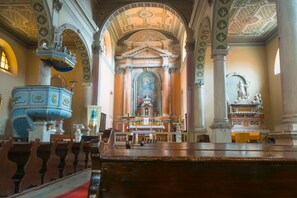 L’intérieur d’une église, avec un autel central, des bancs et un grand baptistère.