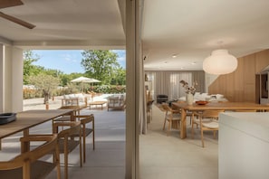 A modern interior with a dining area, kitchen, and a view of the outdoors. - Nareo Villa Collection With Private Pool (Sveta Nedelja)